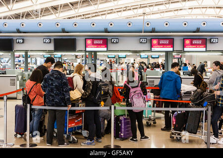 Japan, Kansai Airport, KIX. Interieur, Terminal 1. International check-in. Warteschlangen der Asiatischen Personen mit Gepäck Trolleys, in der an den Arbeitsplätzen zu überprüfen. Stockfoto