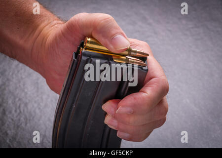 Mannes hand Laden von Munition im Magazin.223/556 auf Schiefer Fläche Stockfoto