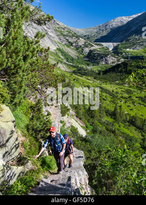 Zwei männliche Wanderer in der Grimsel-Region der Schweizer Alpen, auf einem exponierten und steile Treppe-wie Weg aufsteigend. Stockfoto