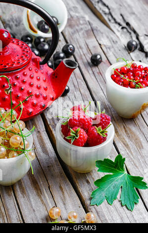 Wasserkocher und Sommer Beeren Johannisbeeren und Himbeeren auf hölzernen Hintergrund Stockfoto