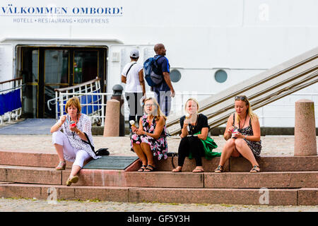 Göteborg, Schweden - Juli 25. 2016: vier Frauen sitzen auf eine Gedenkstätte Steintreppe Eis essen. Eingang zum Res ein Segelboot Stockfoto