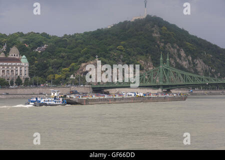Schlepper schiebt Lastkahn unter Elizabeth Brücke am Fluss Donau mit Zitadelle im Hintergrund Stockfoto