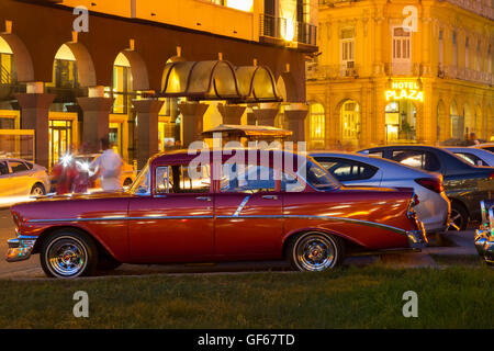 Eine amerikanische Oldtimer mit Hotel Plaza im Hintergrund in der Nacht in Alt-Havanna in der Abenddämmerung.  Havanna, Kuba. Stockfoto