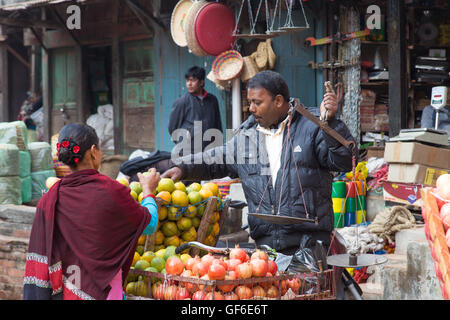 Bhaktapur, Nepal - 5. Dezember 2014: Obst-Verkäufer mit einem Kunden in den Straßen. Stockfoto