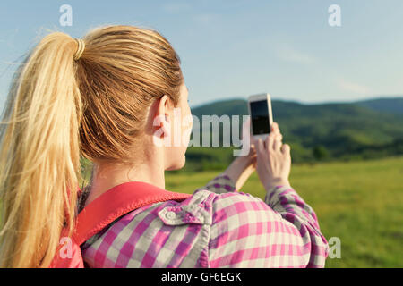 Blonde Frau, Foto mit Ihrem Smartphone auf Berge wandern. Stockfoto