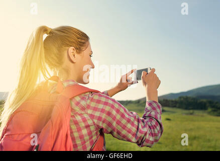 Blonde Frau, Foto mit Ihrem Smartphone auf Berge wandern. Stockfoto