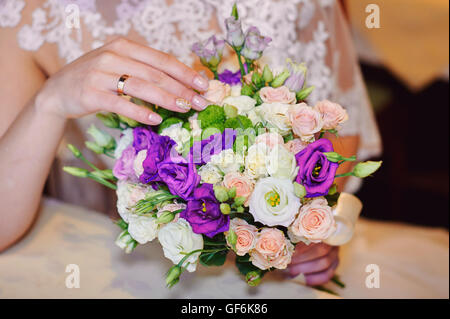 Braut-Hand mit Gold ring einen Hochzeitsstrauß auf Tisch Stockfoto