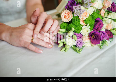 Braut-Hand mit Gold ring einen Hochzeitsstrauß auf Tisch Stockfoto