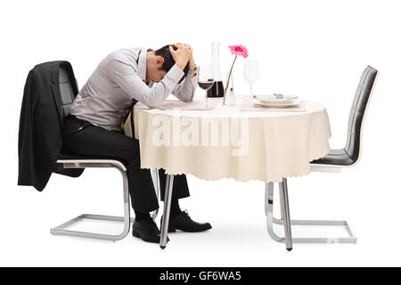 Verzweifelten Kerl sitzt allein an einem Tisch im Restaurant mit dem Kopf nach unten isoliert auf weißem Hintergrund Stockfoto