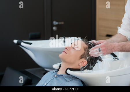 Nahaufnahme eines jungen Mannes, der seine Haare gewaschen im Friseursalon Stockfoto