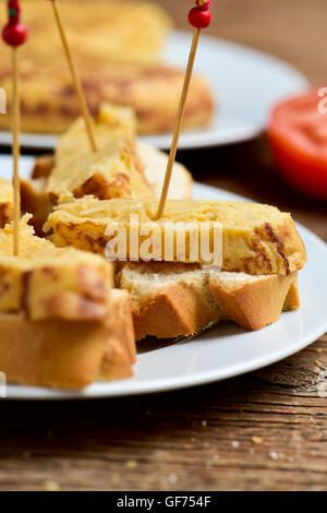 Nahaufnahme einer Platte mit Tortilla de Patatas, spanisches Omelett, diente als Tapas auf geschnittenem Brot und einem Zahnstocher durch sie, auf eine ta Stockfoto