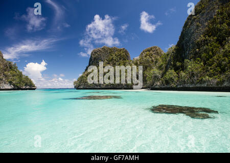 Koralle Bommies wachsen inmitten einer flachen, sandigen Lagune, umgeben von schönen Kalksteininseln in Wayag, Raja Ampat, Indonesien. Stockfoto