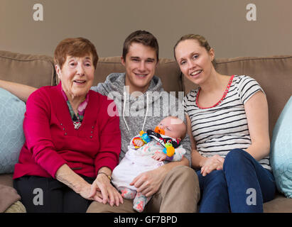 3 Generationen von Menschen, die mehrere Generationen von Menschen sitzen auf einem Sofa mit Baby Stockfoto