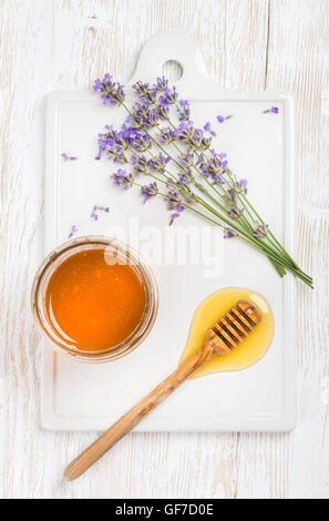 Lavendel Honig im Glas mit Blumen auf weißem Hintergrund Stockfoto