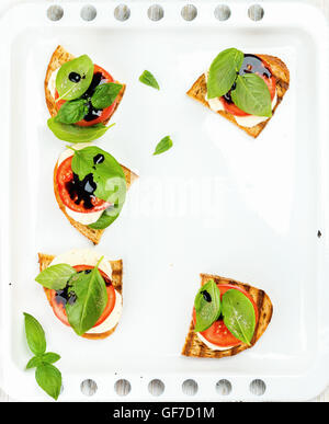 Caprese-Sandwiches mit Tomaten, Mozzarella, Basilikum und Balsamico-Glasur auf Backblech, Textfreiraum weiß Stockfoto