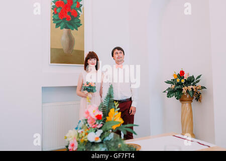 Matthew Braut und Bräutigam bei Anmeldung Standesamt. Süße rote kurzhaarige Frau mit einem Blumenstrauß in Händen Stockfoto