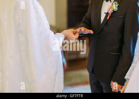 Der Priester Kleider einen Ring am Finger, während kirchliche Hochzeit Bräutigam Stockfoto