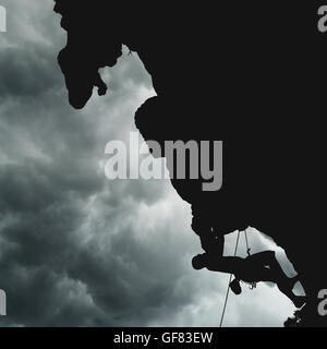 Silhouette eines Kletterers auf einer Klippe während Strom Regenwolke am Himmel Stockfoto