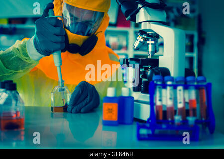 Labortest des Ebola-Virus. Wissenschaftler nimmt Blut aus Reagenzglas in Pipette Mikroskop Studien in biologischen Proben. Stockfoto