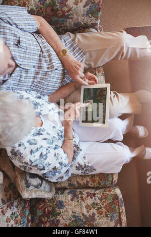 Draufsicht auf älteres Ehepaar, betrachten von Bildern auf digital-Tablette. Ältere Mann und Frau sitzen auf Sofa Bilder auf touch s Stockfoto