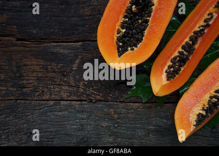 Draufsicht Reife Papaya mit grünen Blatt auf alten hölzernen Hintergrund. Stockfoto