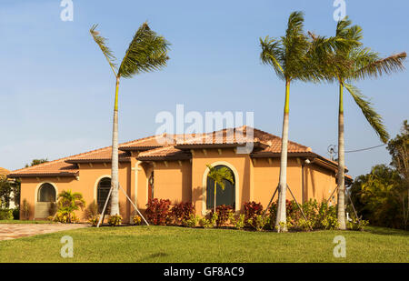 Typische Südwestflorida Betonblock und Stuck zu Hause, in der Landschaft mit Palmen, tropischen Pflanzen und Blumen, Rasen Stockfoto