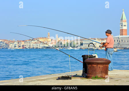 Ein Angler Angeln mit Blick auf den Dogenpalast und Campanile von San Marco in Venedig, Italien Stockfoto