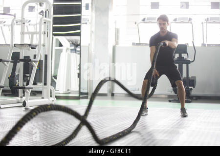 Junger Mann mit kämpfen Seil im Fitness-Studio trainieren Stockfoto