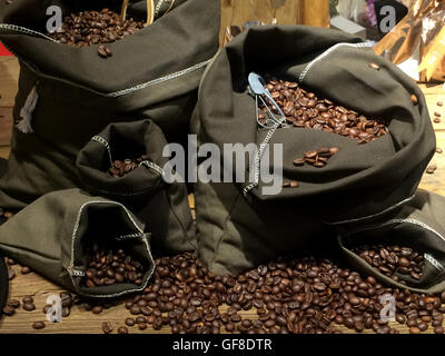 Kaffeebohnen auf Taschen über rustikale Holz Hintergrund Stockfoto