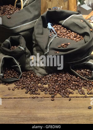 Kaffeebohnen auf Taschen über rustikale Holz Hintergrund Stockfoto