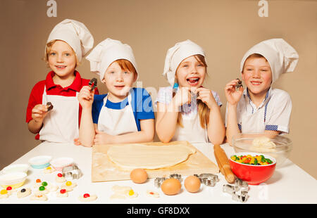 Vier glückliche kleine Köche, Bäcker spielen Stockfoto