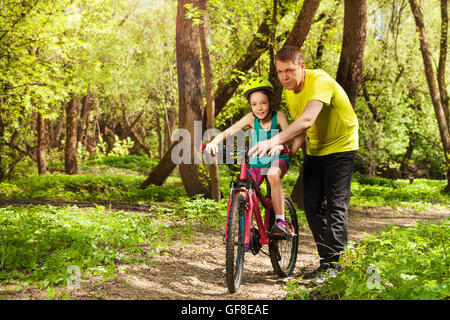 Vater lehrt Tochter draußen Fahrrad fahren Stockfoto