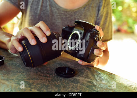 Closeup von einem kaukasischen Jüngling Herausnehmen der Linse von seiner Spiegelreflex-Kamera im freien Stockfoto