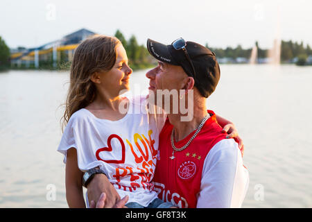 Vater seiner Tochter vor einem See hielt, kurz vor Sonnenuntergang im Sommer Stockfoto