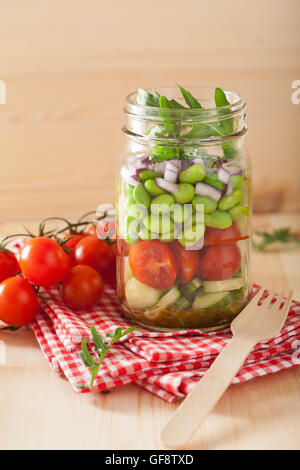 gesunder Gemüsesalat im Einmachglas: Tomaten, Gurken, Sojabohnen, Zwiebeln Stockfoto