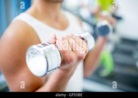 EIGENTUM FREIGEGEBEN. -MODELL VERÖFFENTLICHT. Junger Mann mit Hanteln beim trainieren, close-up. Stockfoto