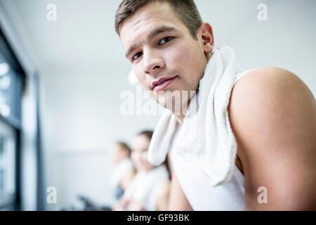 EIGENTUM FREIGEGEBEN. -MODELL VERÖFFENTLICHT. Porträt des jungen Mannes mit Serviette um Hals im Fitness-Studio, close-up. Stockfoto