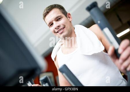 EIGENTUM FREIGEGEBEN. -MODELL VERÖFFENTLICHT. Porträt des jungen Mannes Training mit Serviette um Hals im Fitness-Studio, close-up. Stockfoto