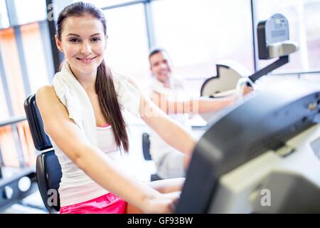 EIGENTUM FREIGEGEBEN. -MODELL VERÖFFENTLICHT. Porträt der jungen Frau mit Serviette um den Hals im Fitness-Studio, lächelnd. Stockfoto