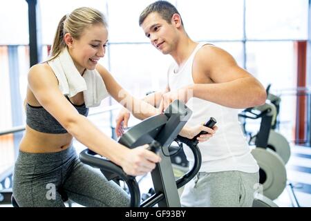 EIGENTUM FREIGEGEBEN. -MODELL VERÖFFENTLICHT. Mann anweist Frau Heimtrainer im Fitness-Studio, verwenden Lächeln auf den Lippen. Stockfoto