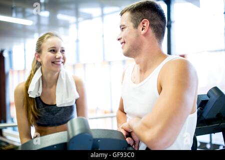 EIGENTUM FREIGEGEBEN. -MODELL VERÖFFENTLICHT. Junger Mann und Frau miteinander zu reden, während der Arbeit im Fitness-Studio, lächelnd. Stockfoto
