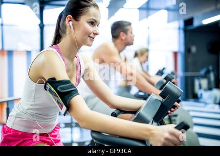 EIGENTUM FREIGEGEBEN. -MODELL VERÖFFENTLICHT. Junge Frau Musikhören während der Arbeit im Fitnessstudio. Stockfoto