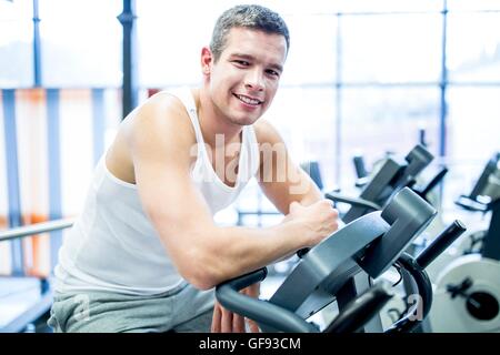 EIGENTUM FREIGEGEBEN. -MODELL VERÖFFENTLICHT. Porträt des jungen Mannes ruhen, während die Arbeit im Fitness-Studio, lächelnd. Stockfoto