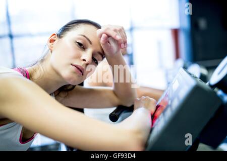 EIGENTUM FREIGEGEBEN. -MODELL VERÖFFENTLICHT. Close-up jungen Frau ruht auf Heimtrainer im Fitness-Studio, Porträt. Stockfoto