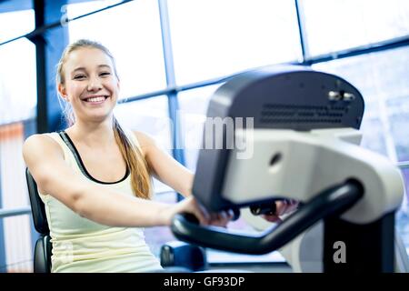 EIGENTUM FREIGEGEBEN. -MODELL VERÖFFENTLICHT. Porträt der jungen Frau auf Heimtrainer im Fitness-Studio trainieren. Stockfoto