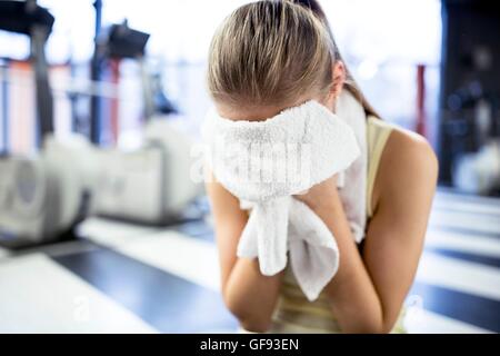 EIGENTUM FREIGEGEBEN. -MODELL VERÖFFENTLICHT. Junge Frau wischte sich den Schweiß mit Handtuch nach dem Training im Fitness-Studio. Stockfoto