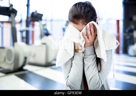 EIGENTUM FREIGEGEBEN. -MODELL VERÖFFENTLICHT. Süße junge Frau wischte sich ihren Schweiß nach dem Training im Fitness-Studio. Stockfoto