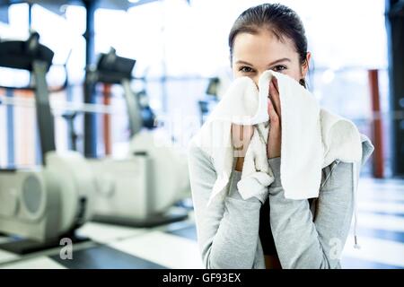 EIGENTUM FREIGEGEBEN. -MODELL VERÖFFENTLICHT. Süße junge Frau wischte sich ihren Schweiß nach dem Training im Fitness-Studio. Stockfoto