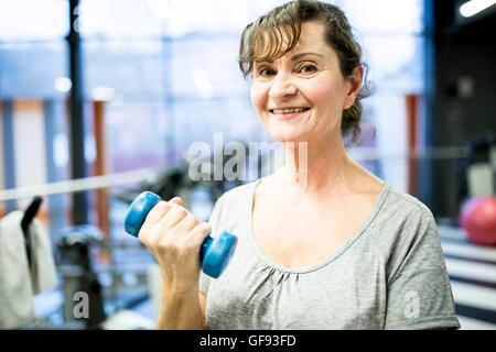 EIGENTUM FREIGEGEBEN. -MODELL VERÖFFENTLICHT. Porträt senior Frau mit Hantel im Fitness-Studio. Stockfoto