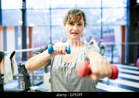 EIGENTUM FREIGEGEBEN. -MODELL VERÖFFENTLICHT. Porträt senior Frau mit Hantel im Fitness-Studio. Stockfoto